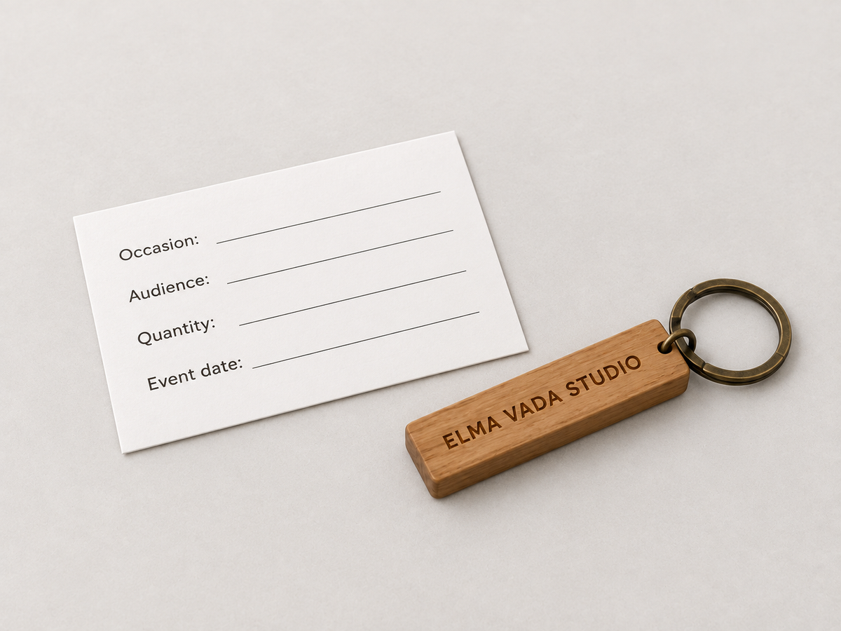 Wooden Elma Vada Studio keychain beside a blank event brief card with four labeled fields.
