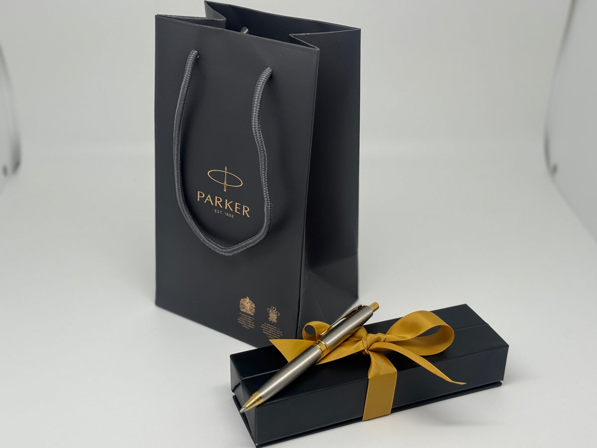 Gift bag, ribbon-tied box and personalized pen presented as a corporate gift set.