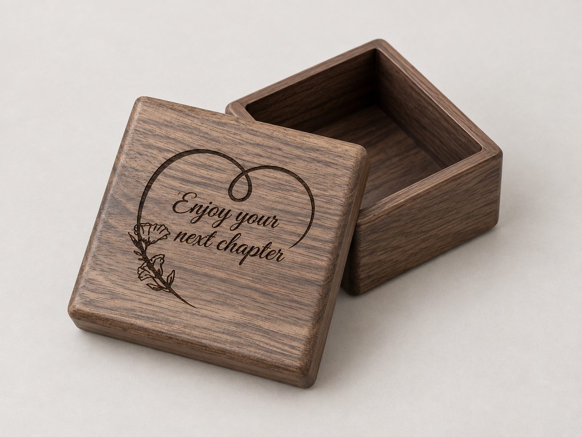 Wooden keepsake box with an open lid engraved Enjoy Your Next Chapter and a botanical flourish.