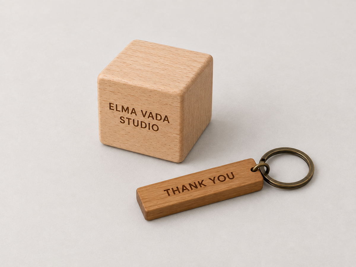 Wooden cube engraved Elma Vada Studio beside a wooden Thank You keychain with a metal ring.